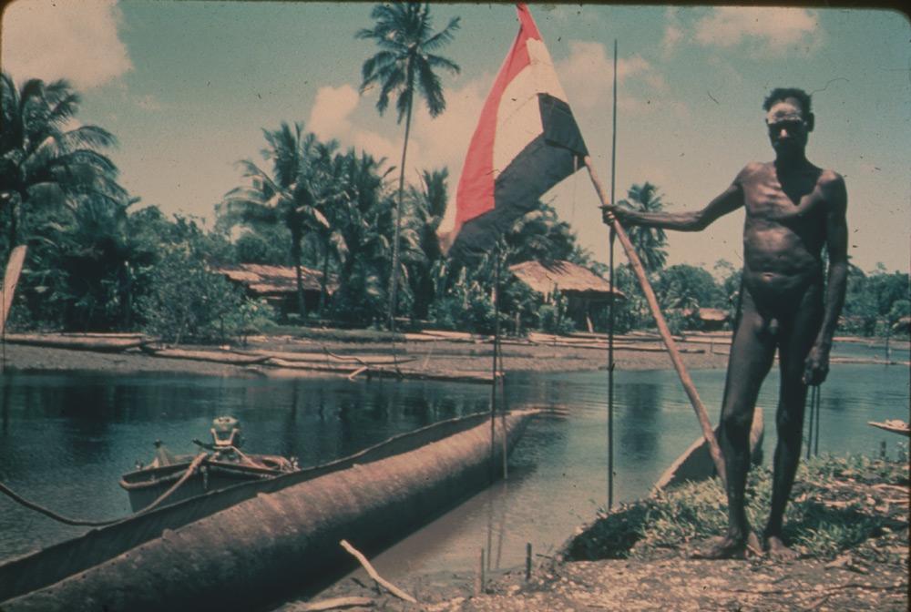 BD/30/29 - 
Village scape, Asmat man with the Dutch flag
