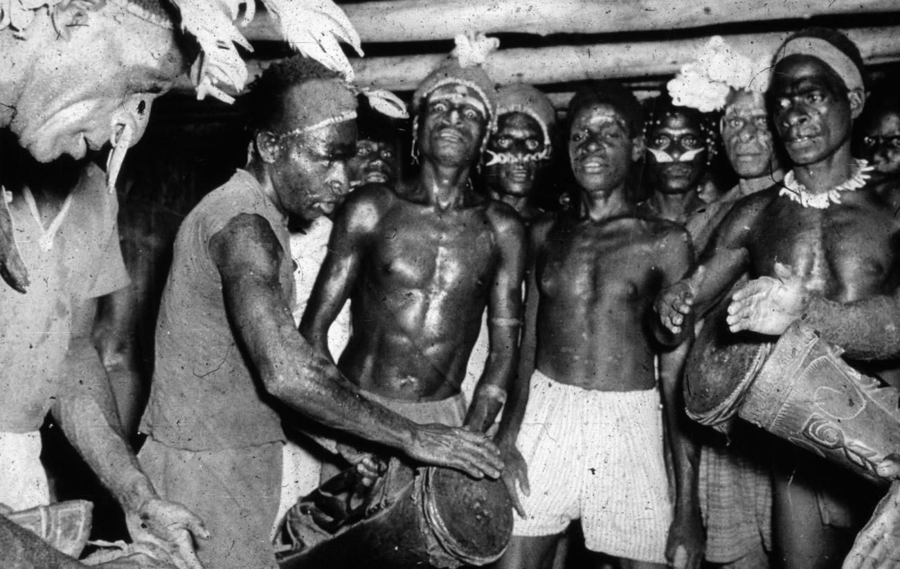 BD/66/184 - 
Asmat, mannen met trommels in het mannenhuis 
