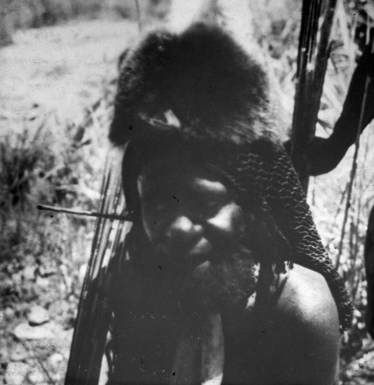 BD/66/461 - 
Portret van een Papoea-man met pijlenbundel en een hoofdtooi van koeskoesbont
