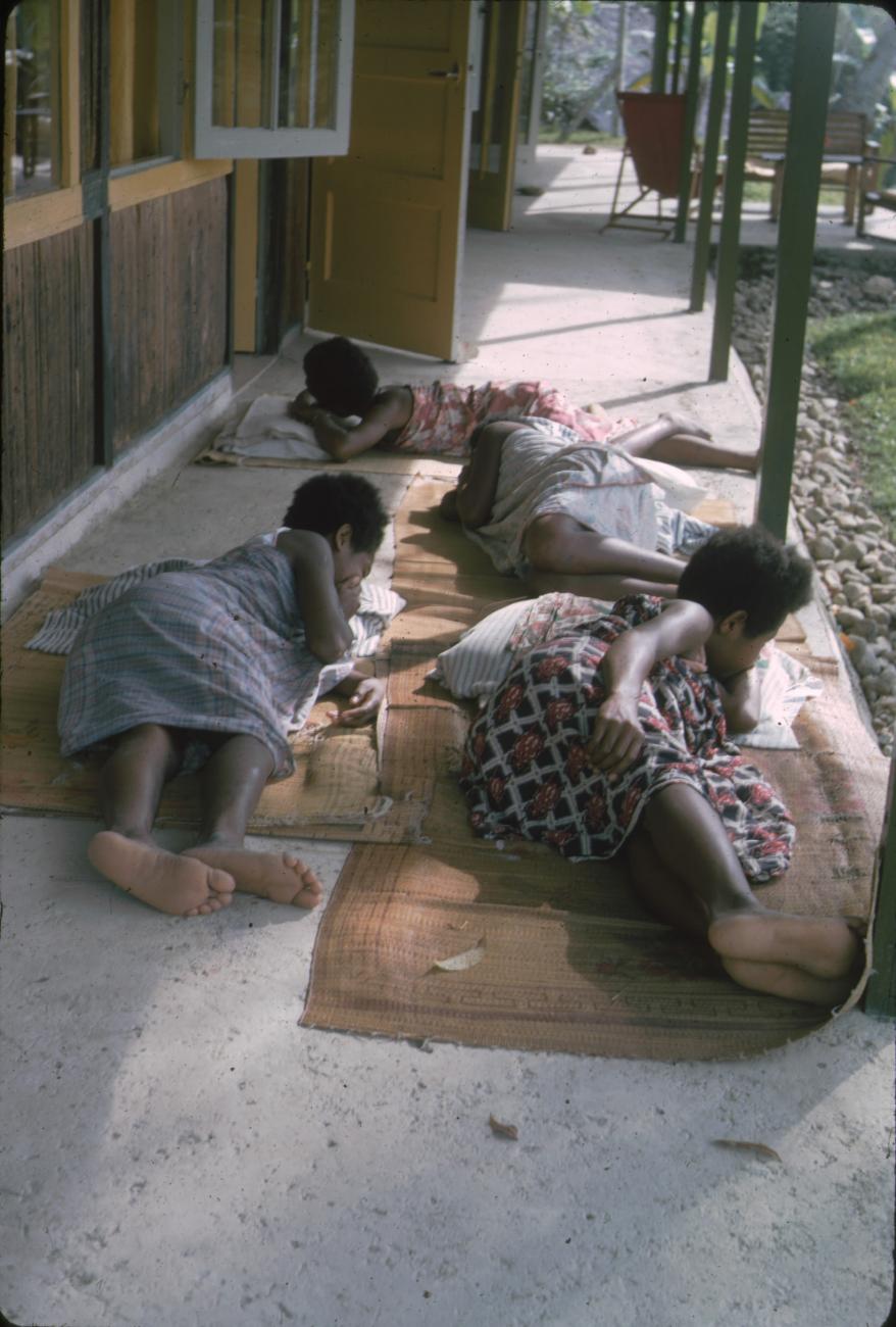BD/171/102 - 
Meisjes rusten op rieten matjes.
