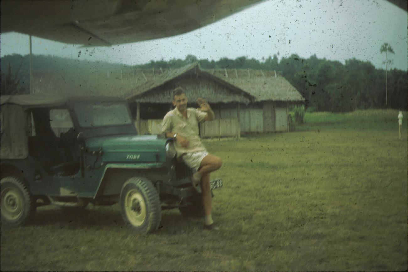 BD/171/249 - 
Westerse man poseert voor jeep op luchthaven.
