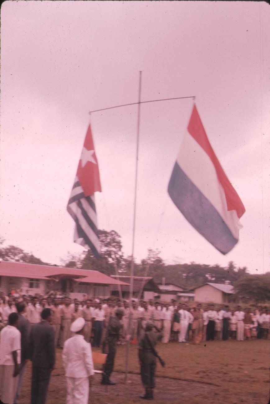 BD/171/25 - 
Festiviteit, vlaggenmast met Nederlandse vlag en Papoeavlag.
