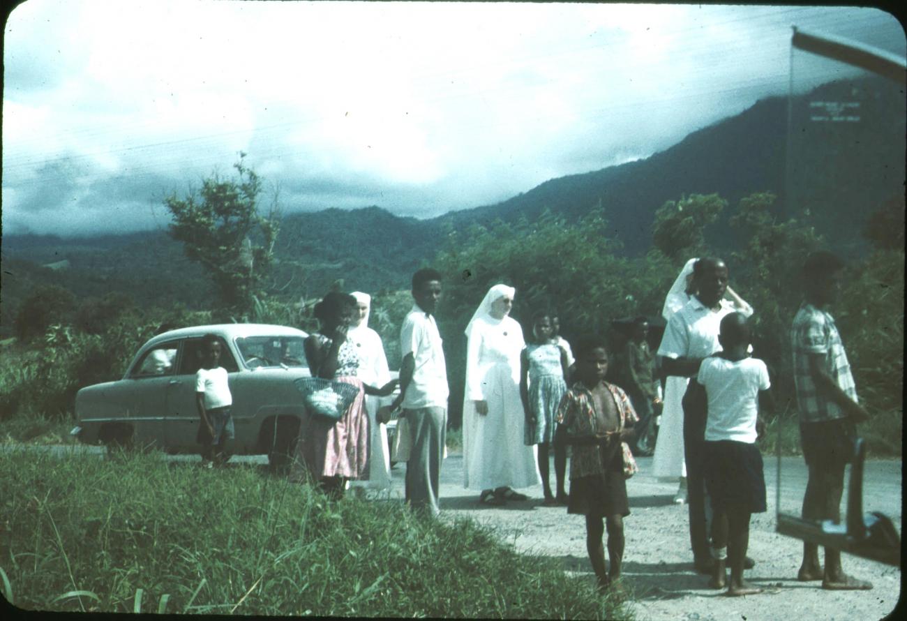 BD/171/344 - 
Groepsfoto nonnen en kinderen bij weg, auto op achtergrond.
