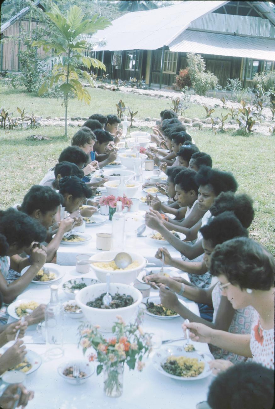 BD/171/359 - 
Jonge vrouwen en westerse vrouwen aan maaltijd in openlucht.
