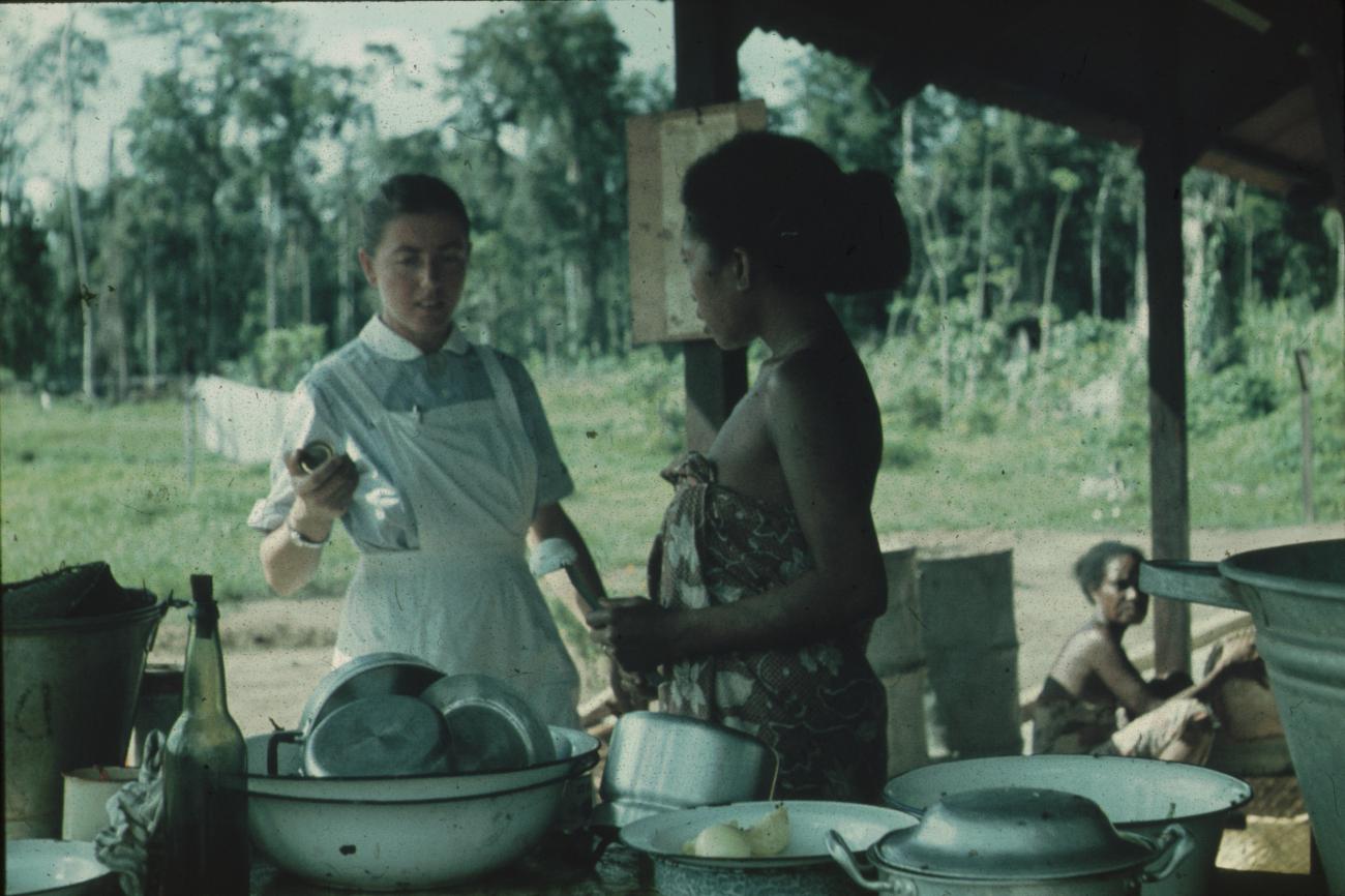 BD/171/584 - 
Vrouwen waarvan een westers temidden van keukenspullen.
