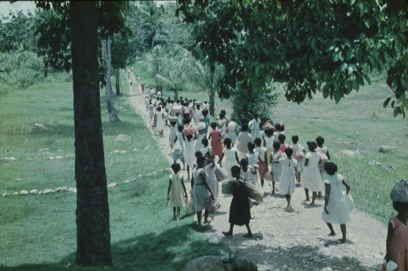 BD/171/1355 - 
Vrouwelijke leerlingen met bagage lopend over weg.
