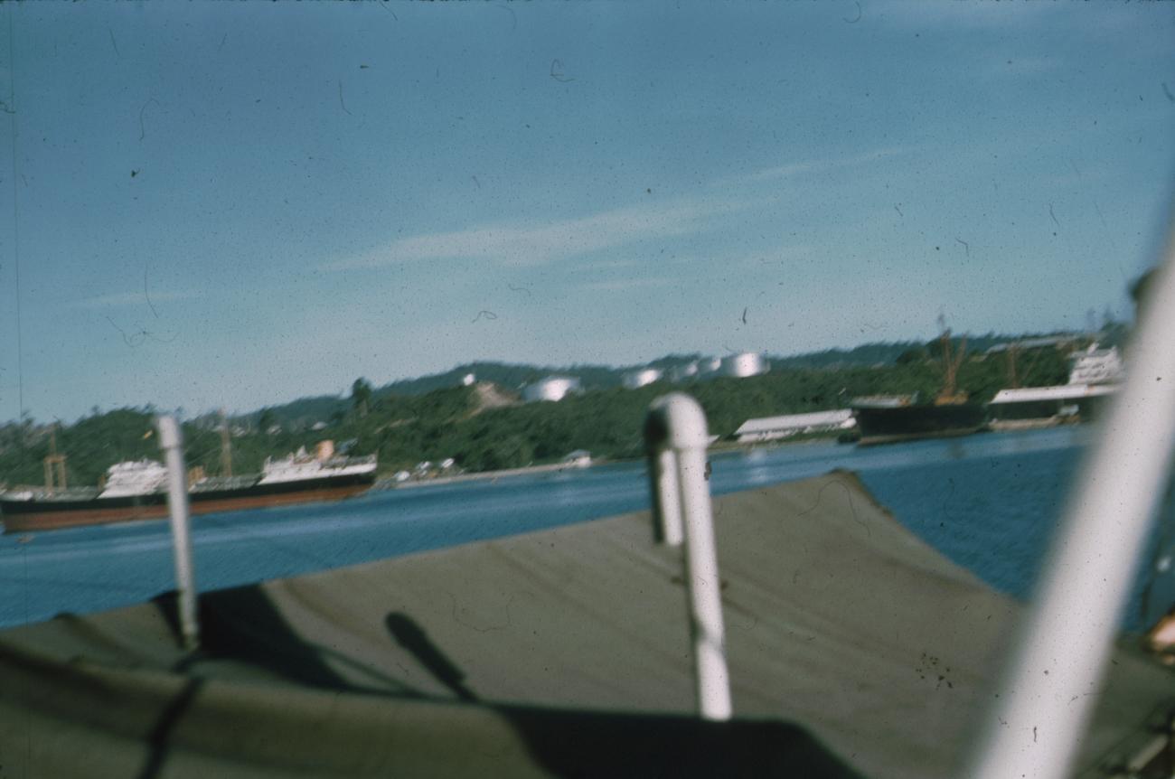 BD/171/678 - 
Foto kust vanaf schip; aangemeerde schepen en oliereservoirs.
