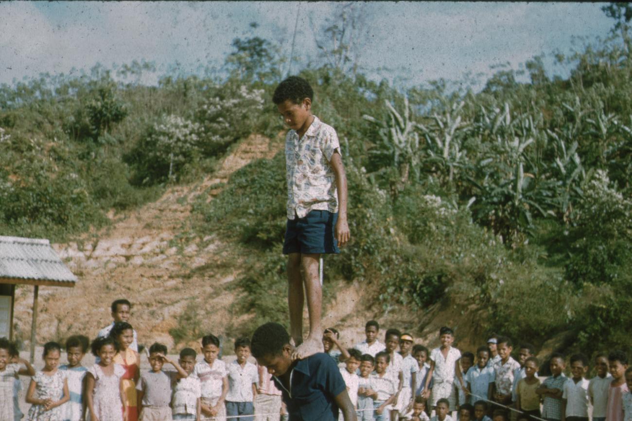 BD/171/698 - 
Kind staat met voeten op schouders ander kind
