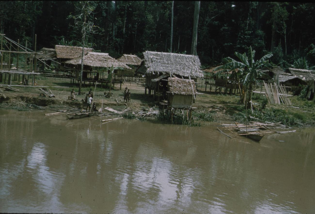 BD/171/950 - 
Kust met rieten hutten, prauwen in het water.
