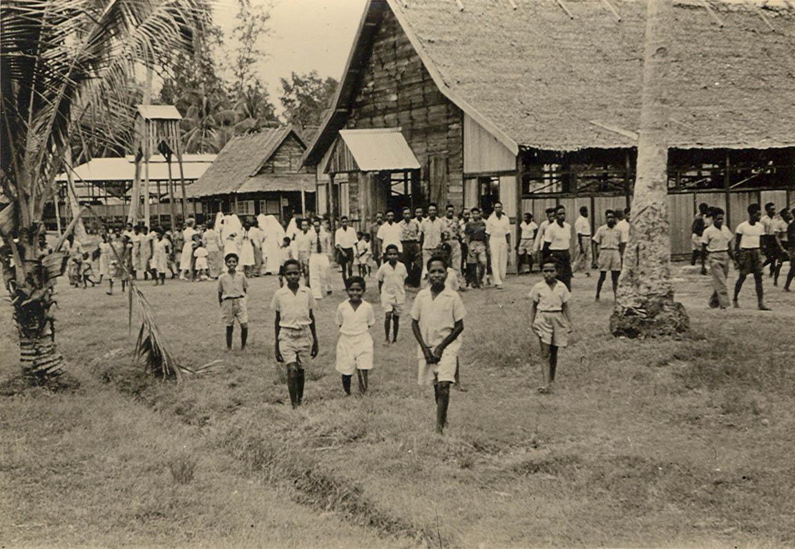 BD/269/1184 - 
Leerlingen van het internaat in Kokonau bij het uitgaan van de kerk, Kerstmis 1957
