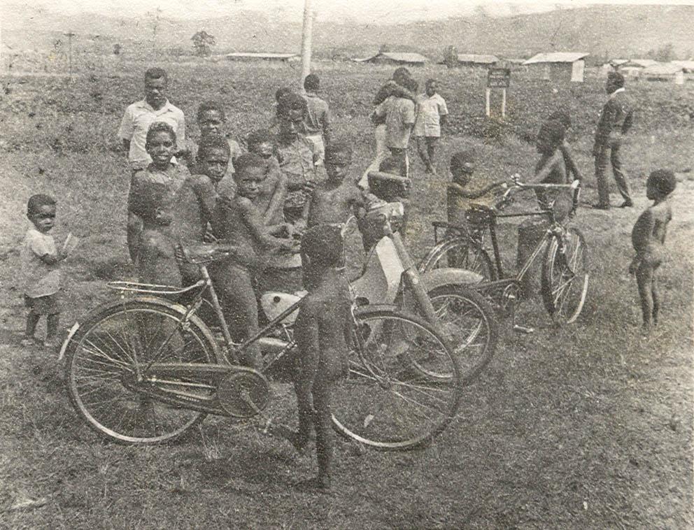 BD/269/1238 - 
Groep Papoea-kinderen bekijkt fietsen en brommer
