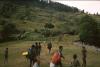 BD/166/183 Dragers lopen over veld in dorp
