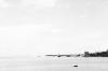 BD/133/687 Panorama van zeekust of rivieroever met nederzetting en aangemeerd schip