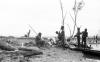 BD/133/69 Tocht Merauke-Kapi: Mannen aan de oever van de rivier bij aangespoeld hout