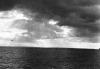 BD/133/855 Kalme zee met kustlijn en donkere wolken