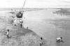 BD/133/946 Getijdelandschap met met drooggevallen zeilschip en langs de oevers vissende Papoea's 