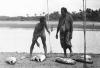 BD/133/952 Papoeaman en -vrouw met gevangen vis en vistuig aan de oever