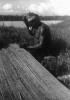 BD/216/172 Man met koeskoesmuts en neusversiering bindt een vloermat van bamboe