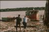 BD/30/64 Asmatman helpt blanke vrouw door modder naar boot op rivier