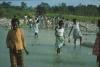 BD/171/101 Vrouwen lopen door het water vol met keien