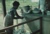 BD/171/583 Vrouw wast kleren bij een waterkraan