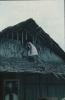 BD/171/1372 Vrouw op huis met rieten dak.